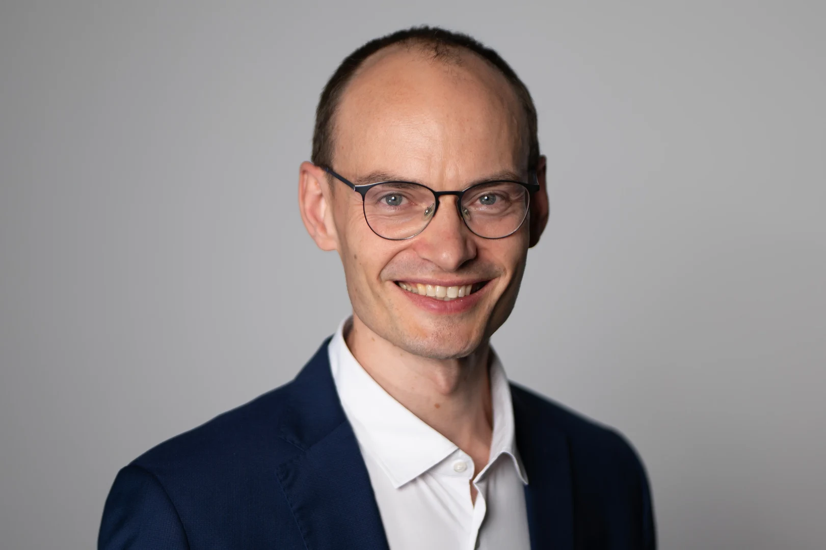 Eine Wissenschaftlerin und ein Wissenschaftler arbeiten hinter einer Glasfassade und mischen Chemikalien mit Großgeräten.