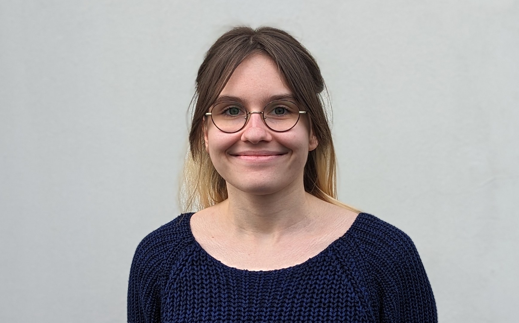 Eine Wissenschaftlerin und ein Wissenschaftler arbeiten hinter einer Glasfassade und mischen Chemikalien mit Großgeräten.
