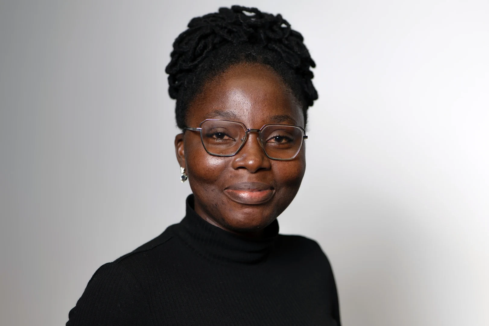 Eine Wissenschaftlerin und ein Wissenschaftler arbeiten hinter einer Glasfassade und mischen Chemikalien mit Großgeräten.