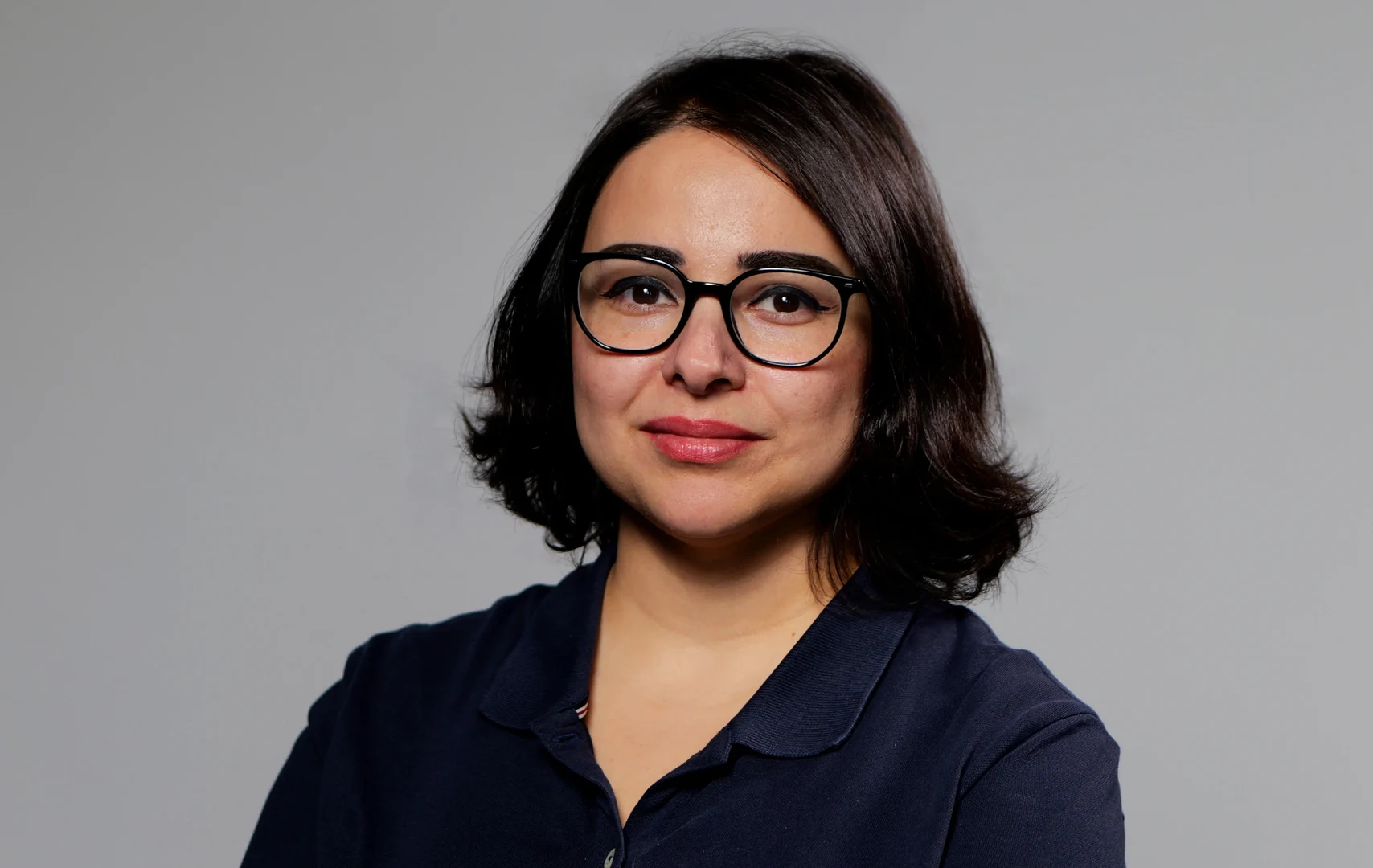 Eine Wissenschaftlerin und ein Wissenschaftler arbeiten hinter einer Glasfassade und mischen Chemikalien mit Großgeräten.